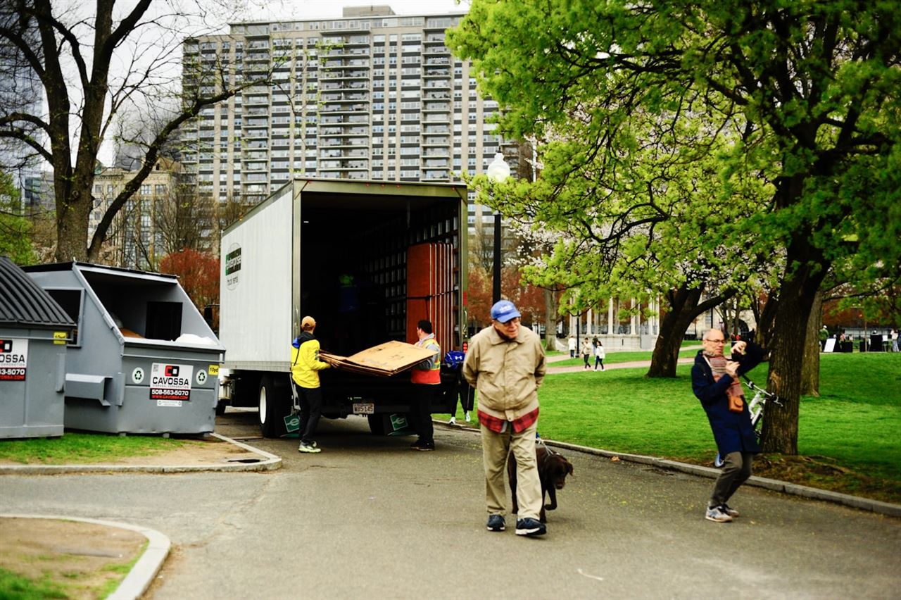 Two movers unloading furniture from the back of a removal van on a city street